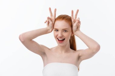 Yakın çekim güzel genç kadının göğüsleri gri, kaplama banyo havlusu ile iki parmak işareti gösterir.