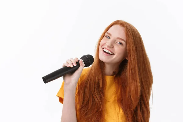Imagen de una mujer feliz con el pelo rizado cantando mientras sostiene el micrófono aislado sobre fondo blanco — Foto de Stock