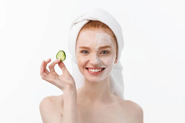 Vonzó fiatal nő szép tiszta bőr. Fehér maszkot, és uborka. Kozmetikai kezelések és kozmetológiai spa kezelés. Fehér háttér — Stock Fotó