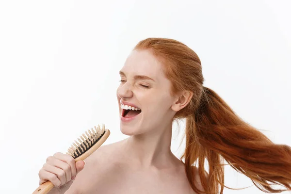 Photo of cheerful smiling freckled ginger young woman combs her long red hair, glad to prepare for date with boyfriend, isolated over white background — Stock Photo, Image