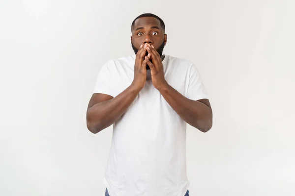 Portret van geschokte jonge Afro-Amerikaanse man het dragen van witte lege T-shirt te kijken naar de camera in verrassing, verbijsterd met een aantal ongelooflijke verhaal. — Stockfoto