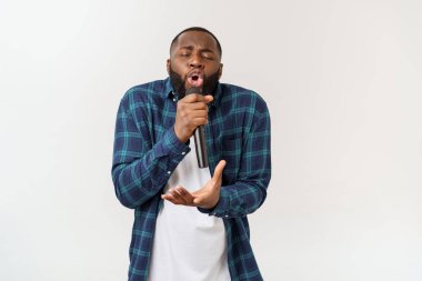 Mikrofon şarkı şarkı tutan neşeli pozitif şık yakışıklı Afrikalı adam portresi. Beyaz arka planda yalıtılmış.