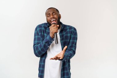 Mikrofon şarkı şarkı tutan neşeli pozitif şık yakışıklı Afrikalı adam portresi. Beyaz arka planda yalıtılmış.