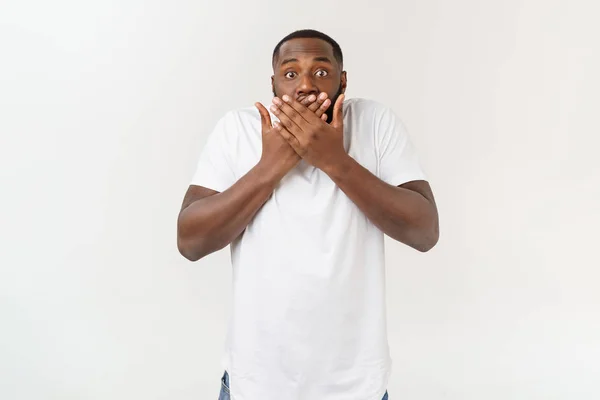 Portret van geschokte jonge Afro-Amerikaanse man het dragen van witte lege T-shirt te kijken naar de camera in verrassing, verbijsterd met een aantal ongelooflijke verhaal. — Stockfoto