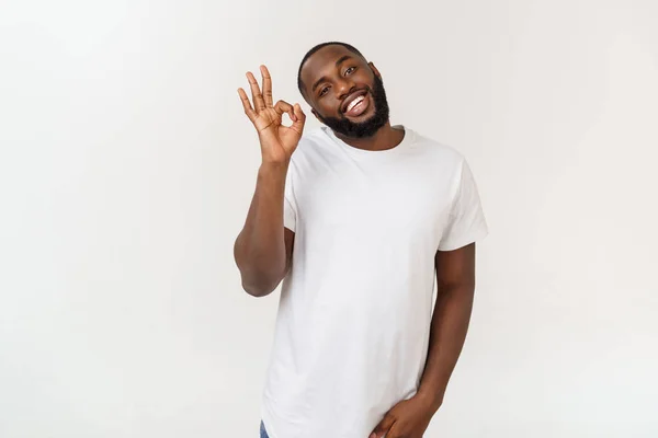 Retrato de un hombre afro-americano feliz mostrando un signo aceptable y sonriente, sobre fondo blanco . — Foto de Stock