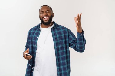 Rahat giysiler içinde Yakışıklı Afro Amerikalı adam bir akıllı telefon kullanarak müzik dinliyor ve gülümseyerek.