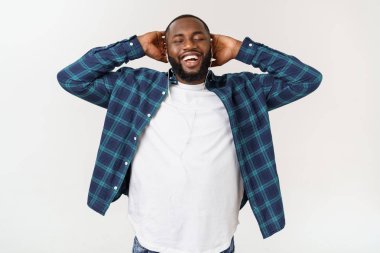 Rahat giysiler içinde Yakışıklı Afro Amerikalı adam bir akıllı telefon kullanarak müzik dinliyor ve gülümseyerek.