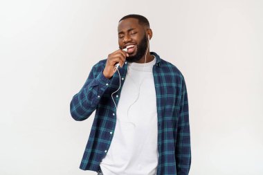 Rahat giysiler içinde Yakışıklı Afro Amerikalı adam bir akıllı telefon kullanarak müzik dinliyor ve gülümseyerek.