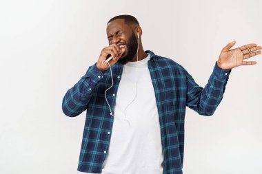 Rahat giysiler içinde Yakışıklı Afro Amerikalı adam bir akıllı telefon kullanarak müzik dinliyor ve gülümseyerek.