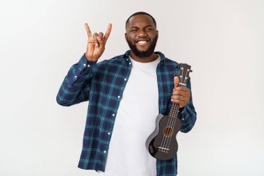 Genç ve yakışıklı Afro-Amerikan adam beyaz arka planda ukulele çalıyor.,