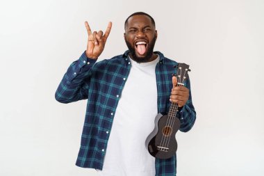 Genç ve yakışıklı Afro-Amerikan adam beyaz arka planda ukulele çalıyor.,