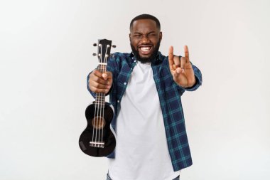 Genç ve yakışıklı Afro-Amerikan adam beyaz arka planda ukulele çalıyor.,