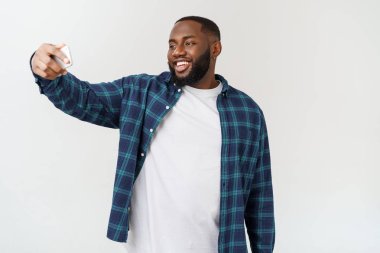 Genç Afro-Amerikan siyah adam gülümsüyor mutlu bir şekilde cep telefonuyla kendi portresini çekiyor..