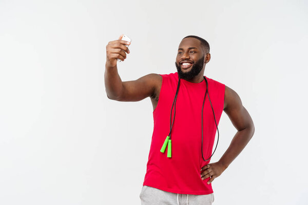 Portrait happy young african man posing isolated over grey background take a selfie by phone with rope and sport wear.
