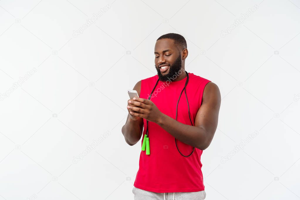 Mature fit African American man texting on mobile and holding elastic rope.