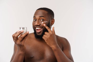 Yüzünde krem uygulayarak gülümseyen Afro adam. Mans Cilt Bakımı kavramı