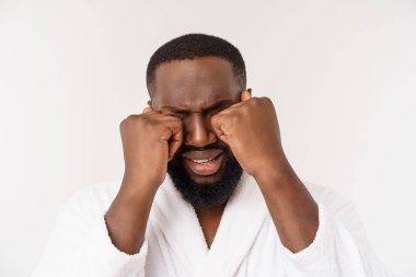 Genç African American Man izole beyaz arka plan üzerinde bornoz giyiyor yorgun görünümlü ve depresyon sorunları ile sıkılmış.