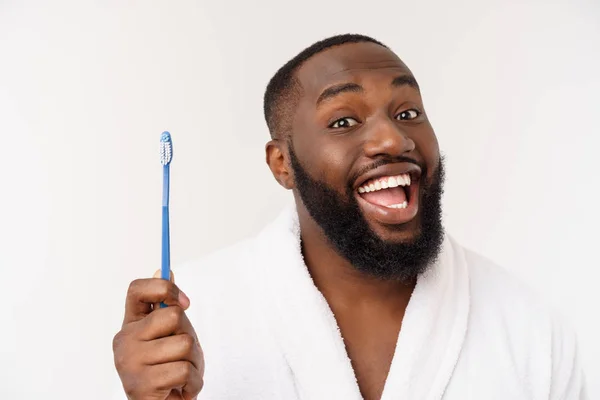 Retrato de un feliz joven oscuro-ano cepillándose los dientes con pasta de dientes negro sobre un fondo blanco . — Foto de Stock