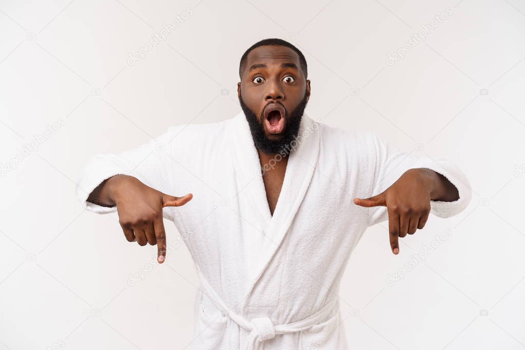 Black guy wearing a bathrobe pointing finger with surprise and happy emotion. Isolated over whtie background.
