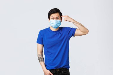 Different emotions, social distancing, quarantine on covid-19 and lifestyle concept. Are you insane. Furious and pissed young asian guy scolding person acting stupid or crazy, roll finger on temple