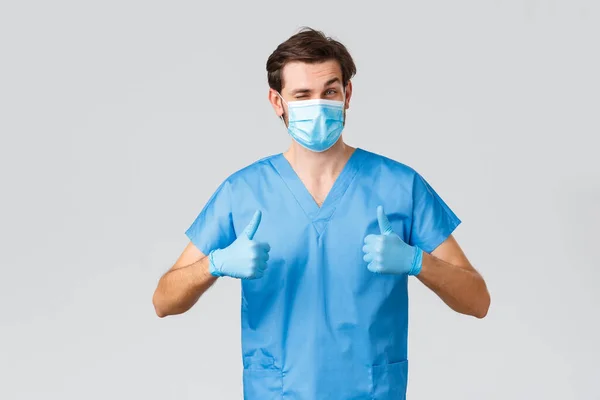 コロナウイルスの発生、病気と戦う医療従事者、病院の概念。医療用マスク、手袋、スクラブの熱狂的な医師、承認の親指アップを表示、推奨または製品を保証 — ストック写真
