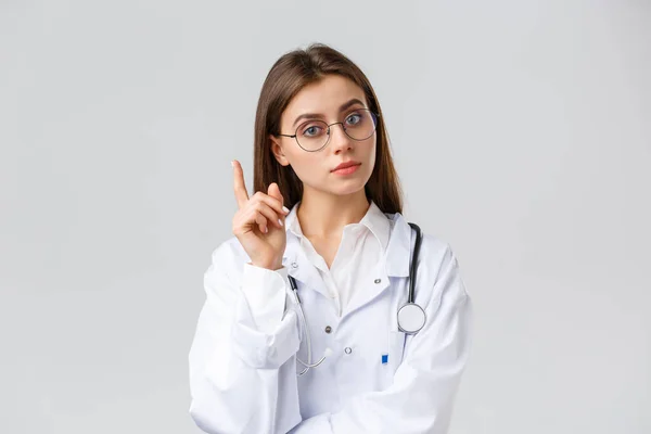 Gesundheitspersonal, Medizin, Versicherung und Covid-19-Pandemiekonzept. Smart professionelle Ärztin in weißen Peelings und Brille, haben Idee, Vorschlag, heben Zeigefinger Eureka Zeichen — Stockfoto