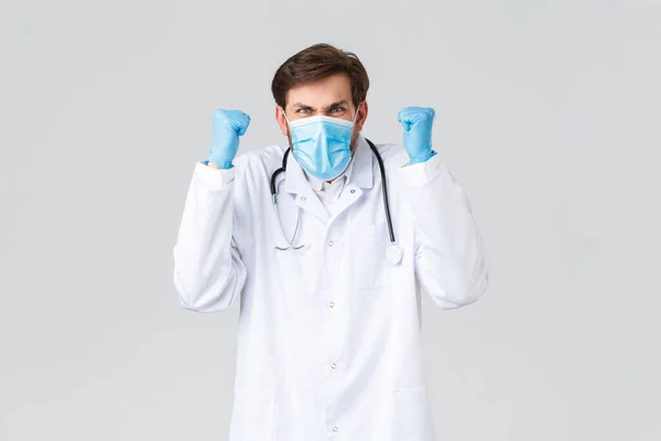 Hospital, healthcare workers, covid-19 treatment concept. Angry and pissed-off doctor in white scrubs, medical mask and gloves, raising hands up, frowning and looking upset or concerned — Φωτογραφία Αρχείου