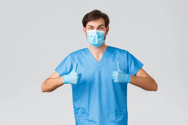 Спалах коронавірусу, працівники охорони здоров'я борються з хворобами, концепцією лікарень. Підтримка і упевненість лікаря, стажування ЕР в чашках, медична маска і рукавички, показати пальцем вгору, схвалення — стокове фото