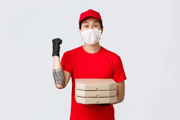 陽気な配達の男拳ポンプ、顧客の家にピザを配達し、宅配便サービスのための巨大なヒントを得たことを祝う。医療用マスクと手袋を着用して — ストック写真