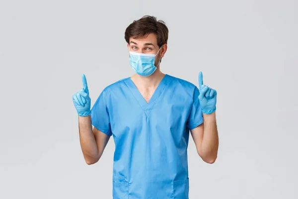Covid-19, vårdpersonal och sjukhuskoncept. Läkare i skrubb, medicinsk mask och handskar talar betydelse tvätta händerna, peka finger upp, ser allvarlig, sjuksköterska arbetar med coronavirus patienter — Stockfoto