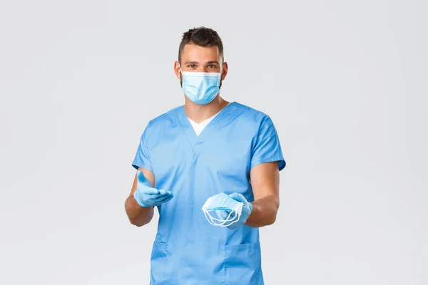 Gezondheidswerkers, covid-19, coronavirus en het voorkomen van virus concept. Knappe verpleegkundige, mannelijke arts in scrubs en persoonlijke beschermingsmiddelen PBM, met medisch masker — Stockfoto