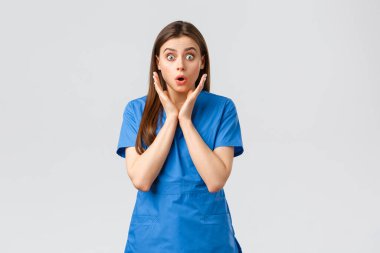 Sağlık çalışanları, virüsü, sigortayı ve ilaç konseptini engelleyin. Şaşırmış hemşire ya da kadın doktor mavi önlüklü, soluk soluğa endişeli görünüyor, yeni Cauvid-19 hastasının hastalandığını duyuyor, kameraya bakıyor