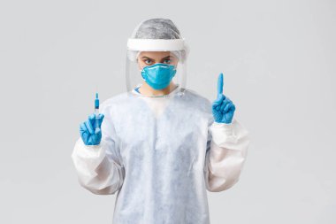 Covid-19, tıbbi araştırma, teşhis, sağlık çalışanları ve karantina konsepti. PPE kostümlü kararlı doktor, kişisel koruyucu ekipman, hasta için koronavirüs aşısı olan şırınga