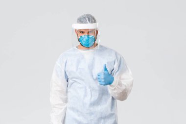 Covid-19 salgını, virüs salgını, klinik ve sağlık çalışanları konsepti. Kişisel koruyucu ekipman ve solunum cihazlarında iyimser kendine güvenen doktor, onay ver, güvence ver ya da garanti et