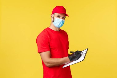 Salgın sırasında hızlı teslimat, covid-19, güvenli nakliye, online alışveriş konsepti. Kırmızı üniformalı ve tıbbi maskeli hoş genç kurye, panoda sırayla, kameraya bak.