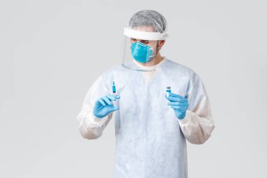 Covid-19, salgın hastalık, virüs salgınıyla mücadele eden sağlık çalışanları. Doktor şırıngayı 19 aşıyla dikkatlice tutuyor, salgın sırasında hastayı tedavi ediyor, koruyucu giysi ve eldiven giyiyor.