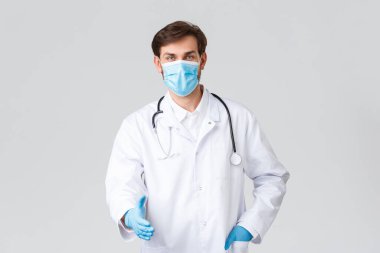 Hastane, sağlık çalışanları, covid-19 tedavi konsepti. Tıbbi maske, önlük ve eldiven giymiş profesyonel ciddi bir doktor. El çabukluğu, hemşirelerle, iş arkadaşlarıyla ya da hastalarla görüşmeler.