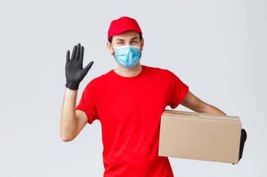 Paketler ve paket teslimatı, karantina teslimatı, nakil emirleri. Kırmızı üniformalı arkadaş canlısı kurye, koruyucu eldivenli yüz maskesi, sipariş kutusunu müşteriye teslim etmek, el sallayarak merhaba demek.