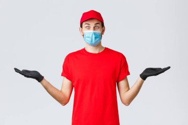 Erzak ve paket teslimatı, covid-19, karantina ve alışveriş konsepti. Şaşkın kurye kırmızı üniformalı, eldivenli ve yüz maskeli afiş ya da şirket tanıtımıyla el ele tutuşuyor.