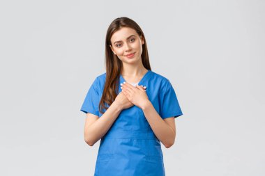 Sağlık çalışanları, virüsü, sigortayı ve ilaç konseptini engelleyin. Dokunulmuş ve pohpohlanmış mavi önlüklü kadın hemşire veya doktor, başını eğ ve kalbe dokun, iltifattan gülümse, hoş bir jest.