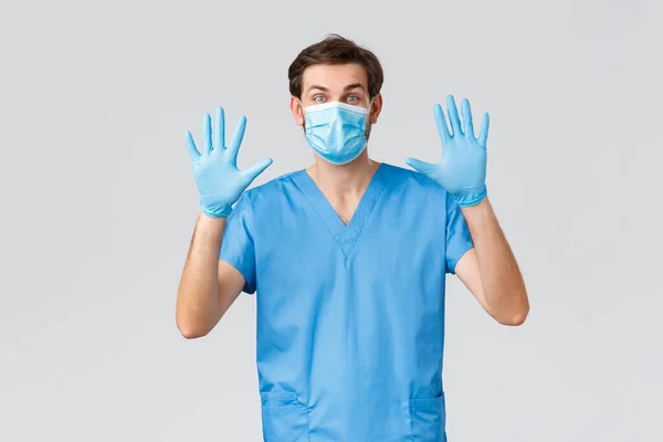 Covid-19, karantän, sjukhus och vårdpersonal koncept. Vänlig läkare i medicinsk mask, handskar och skurar, visar sina händer, nummer tio, förklara säkerhetsåtgärder för att skydda mot coronavirus — Stockfoto
