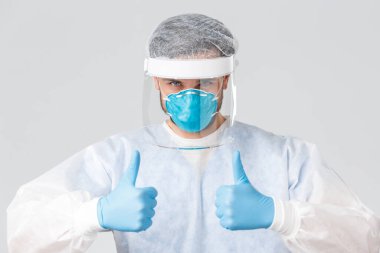 Covid-19, salgın hastalık, virüs salgınıyla mücadele eden sağlık çalışanları. Kendine güvenen profesyonel tıbbi şeyler, hastanedeki doktor baş parmağını kaldırdı, koruyucu kıyafet giydi, klinikte güvenli insanlar yaşıyor, aşı bekledi.