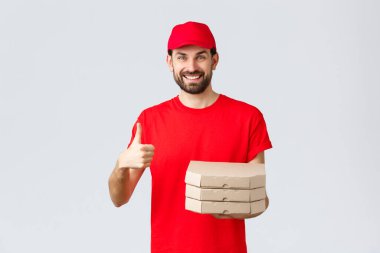 Yemek teslimatı, karantina, evde kalmak ve online konsept sipariş etmek. Kırmızı üniformalı ve tişörtlü arkadaş canlısı, sakallı kurye servisi veya restoranı tavsiye eder, müşteriye pizza verir.