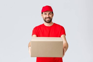 Sipariş teslimatı, online alışveriş ve paket nakliyat konsepti. Kırmızı üniformalı, sakallı, arkadaş canlısı kurye müşterilere paket dağıtıyor, kutuyu müşteriye veriyor.