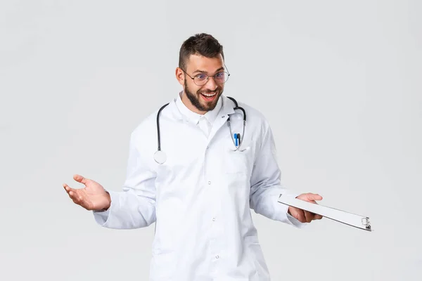 Healthcare workers, medical insurance, clinic lab and covid-19 concept. Surprised and excited doctor in white coat with stethoscope and clipboard, looking patients bed congratulate with good news — Stock Photo, Image