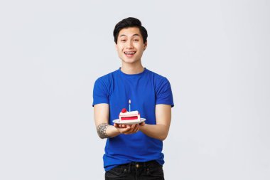 Karantina, ev hayatı ve kutlama konsepti. Neşeli Asyalı adam covid-19 salgını sırasında doğum gününü kutluyor, doğum günü pastası veriyor, gülümsüyor.