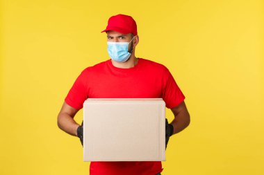 Salgın sırasında hızlı teslimat, covid-19, güvenli nakliye, online alışveriş konsepti. Kararsız veya şüpheci kurye inançsız hisset, isteksiz sipariş kutusunu yanlış kişiye ver, paket kutusunu tut