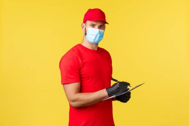 Salgın sırasında hızlı teslimat, covid-19, güvenli nakliye, online alışveriş konsepti. Teslimat şirketinin deposunda çalışan. Paket bilgilerini yazıyor, sipariş bilgilerini not alıyor.