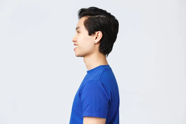 Lifestyle, people emotions and beauty concept. Profile shot of asian hipster guy with earring in blue t-shirt, smiling satisfied after making good new hairuct, hairstyle at barbershop — Stock Photo, Image
