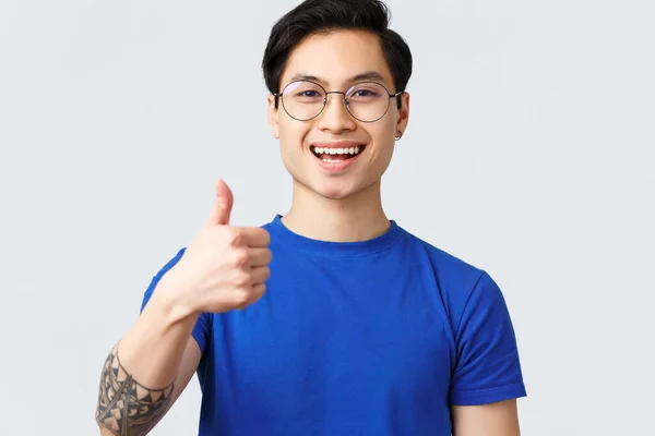 Lifestyle, Menschen Emotionen und Beauty-Konzept. Nahaufnahme eines zufriedenen asiatischen Mannes in Brille und blauem T-Shirt, Daumen hoch, Produkt oder Ort empfehlen, zufrieden mit Friseurbesuch — Stockfoto